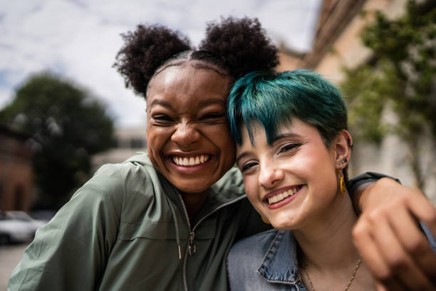Two friends smile joyfully together outdoors.